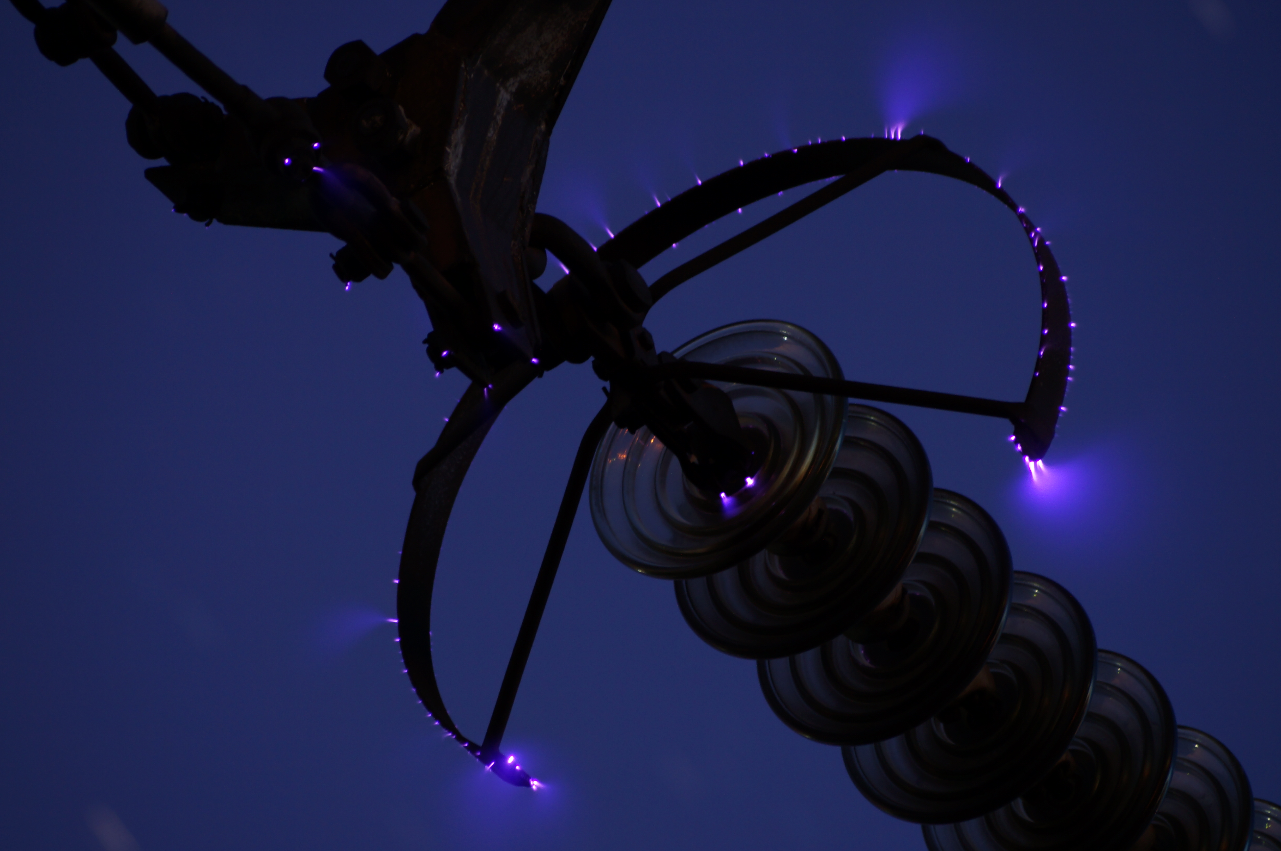 Tampilan jarak menengah menara listrik dengan efek corona discharge di isolator