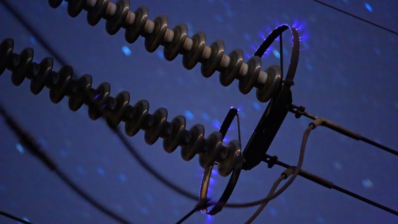 Ilustrasi diagram teknik menunjukkan medan listrik dan ionisasi udara di sekitar konduktor