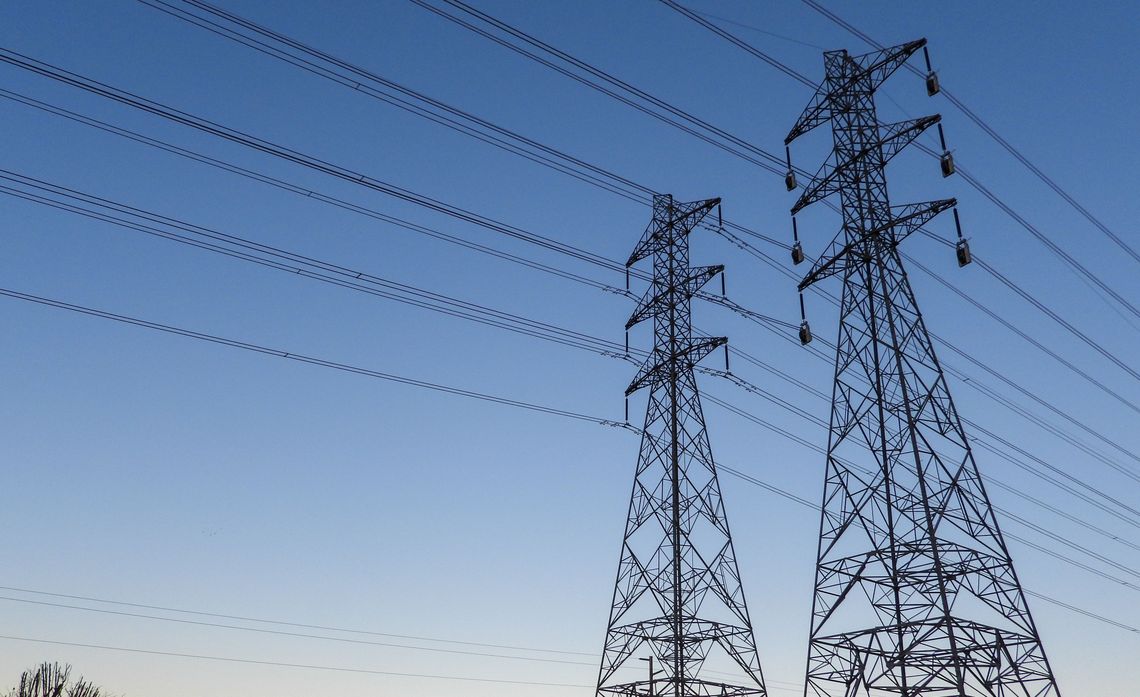 Pekerja menggunakan alat keselamatan melakukan inspeksi di puncak menara transmisi